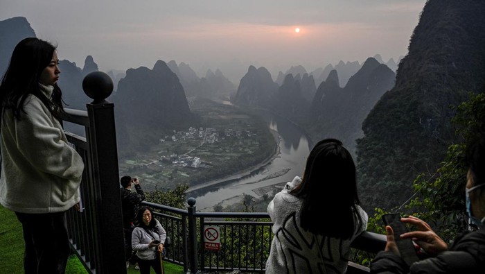 Menikmati Matahari Terbit dari Gugusan Gunung Xianggong China Tourists watch the sunrise at a scenic tourist spot on Xianggong Mountain, on the west bank of Li River in Yangshuo city, in southern China's Guangxi province on February 21, 2023. (Photo by Jade Gao / AFP) (Photo by JADE GAO/AFP via Getty Images)