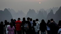 Para turis menyaksikan matahari terbit di Gunung Xianggong, kota Yangshuo, provinsi Guangxi, China Selatan, Selasa (21/2/2023).  