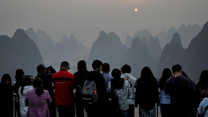 Menikmati Matahari Terbit dari Gugusan Gunung Xianggong China Tourists watch the sunrise at a scenic tourist spot on Xianggong Mountain, on the west bank of Li River in Yangshuo city, in southern China's Guangxi province on February 21, 2023. (Photo by Jade Gao / AFP) (Photo by JADE GAO/AFP via Getty Images)