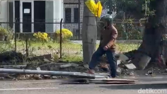 Seorang pengendara berusaha memindahkan tiang rambu lalu lintas yang tumbang di Medan.