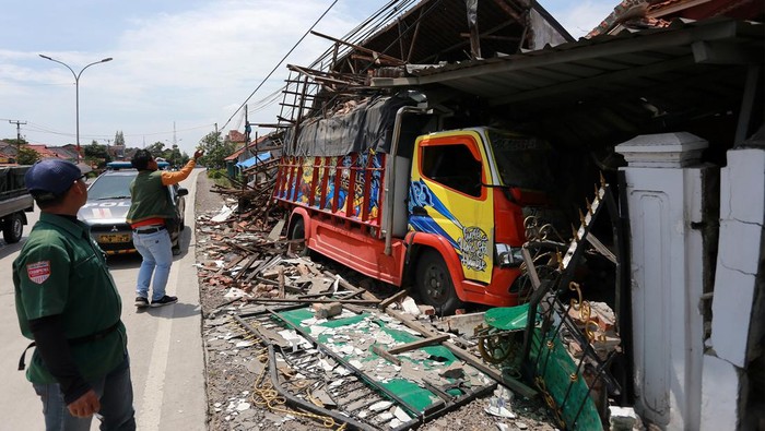 TRUK TABRAK RUMAH DI INDRAMAYU Warga melihat kondisi truk yang menabrak rumah di jalur Pantura Losarang, Indramayu, Jawa Barat, Selasa (21/2/2023). Truk bermuatan pakan ikan yang melaju dari arah Jakarta menuju Cirebon itu menabrak sebuah rumah setelah oleng dan diduga akibat supir mengantuk. ANTARA FOTO/Dedhez Anggara/foc.