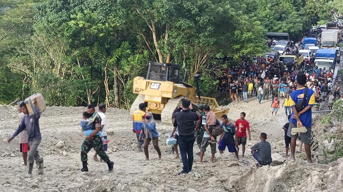 Warga melintasi lokasi longsor di Takari, Kabupaten Kupang, NTT, Senin (20/2/2023).