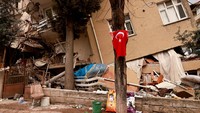 Sebuah bendera Turki digambarkan di dekat properti yang hancur setelah gempa terbaru di provinsi Hatay, Turki, Selasa (21/2/2023).  