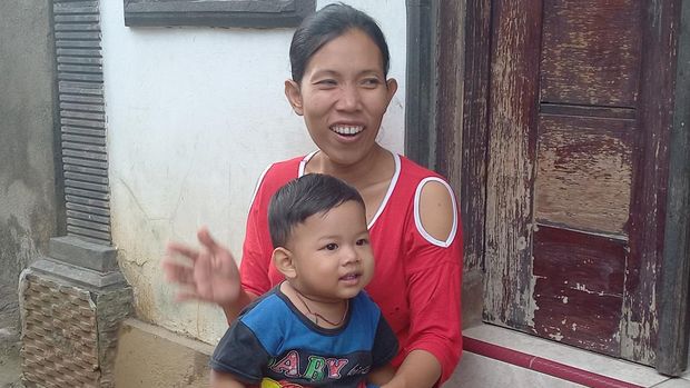 Kadek Sukerti, salah satu penduduk Desa Bengkala yang tuli atau Kolok, Selasa (14/2/2023).Sukerti tengah memangku anaknya yang bukan penyandang disabilitas.