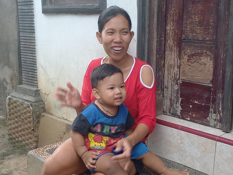 Kadek Sukerti, salah satu penduduk Desa Bengkala yang tuli atau Kolok, Selasa (14/2/2023).
Sukerti tengah memangku anaknya yang bukan penyandang disabilitas.