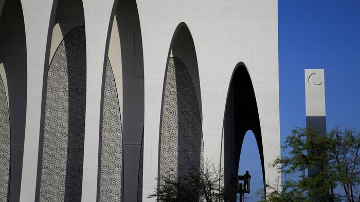 Potret Rumah Ibadah untuk Tiga Agama di Abu Dhabi A man on a crane adds the final touches on the Imam al-Tayeb Mosque at the Abrahamic Family House, in Abu Dhabi, United Arab Emirates, Tuesday, Feb 21, 2023. A new complex, called the Abrahamic Family House, erected on the shores of the Persian Gulf, in the capital of the United Arab Emirates, houses a Catholic church, a Jewish synagogue and an Islamic mosque. (AP Photo/Kamran Jebreili)