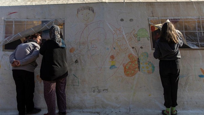 Saat Menlu dan Mendagri Jerman Berjalan di Puing-puing Gempa Turki People living in a camp for displaced families peek through a tent where German Foreign Minister Annalena Baerbock and Interior Minister Nancy Faeser met survivors of the deadly earthquake in Pazarcik, Kahramanmaras, Turkey, February 21, 2023. REUTERS/Eloisa Lopez