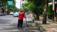 Salah seorang petugas Dinas Kebersihan dan Lingkungan Hidup Surabaya sedang menyapu sampah yang tercecer di Jalan Kayun Surabaya. (Foto: Setiadarma Wisnu/detikJatim)