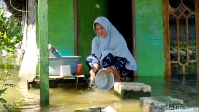 Warga di Lamongan mencuci di depan rumah yang kebanjiran