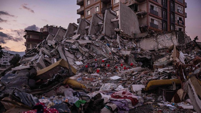 Ogun Sever Okur, 38-year-old Turkish man hangs a ballon on the debris of a collapsed building in Antakya, southern Turkey on February 21, 2023, following the 6.4-magnitude earthquake which struck on February 20, two weeks after a 7.8-magnitude earthquake hit near Gaziantep and has killed more than 44,000 people. - On the side of a busy road in Antakya, dozens of red balloons flutter around, hanging from the ruins. They are 