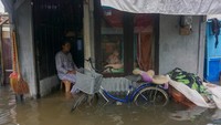 Warga duduk di depan rumahnya yang terendam banjir. Selain akibat curah hujan yang tinggi, banjir tersebut juga disebabkan karena meluapnya air sungai ke permukiman warga.