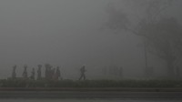 Orang-orang berjalan di sepanjang jalan dekat Gerbang India di tengah kabut asap tebal di New Delhi, Rabu (22/2/2023).