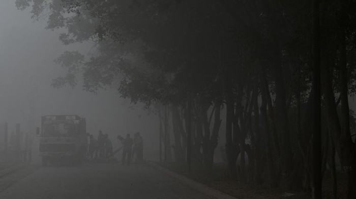 Gelapnya New Delhi Diselimuti Polusi Udara TOPSHOT - People walk along a road near India Gate amid heavy smog in New Delhi on February 22, 2023. (Photo by Arun SANKAR / AFP) (Photo by ARUN SANKAR/AFP via Getty Images)