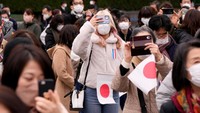 Warga datang dengan membawa bendera Jepang serta sibuk mengabadikan momen ini. Eugene Hoshiko/Pool via REUTERS.