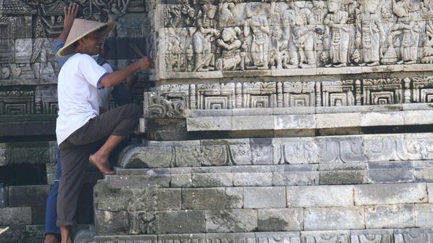 Pekerja membersihkan lumut yang tumbuh pada relief candi Tegowangi menggunakan lidi di Desa Tegowangi, Kediri, Jawa Timur, Selasa (21/2/2023). Candi Hindu yang dibangun pada masa Kerajaan Majapahit sekitar tahun 1400 masehi tersebut dibersihkan lumutnya secara berkelanjutan guna mencegah keroposnya relief terutama saat musim hujan. ANTARA FOTO/Prasetia Fauzani/foc.