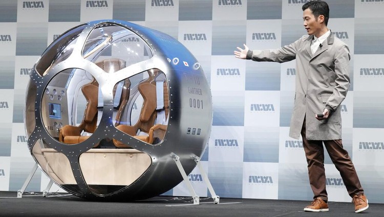Keisuke Iwaya, CEO of a Japanese space development company, Iwaya Giken, unveils a two-seater cabin and a balloon that the company says is capable of rising to an altitude of 15 miles, which is roughly the middle of the stratosphere, as he speaks during a news conference in Tokyo, Tuesday, Feb. 21, 2023. The Japanese startup company announced plans Tuesday to launch a commercial space viewing balloon flight that it hopes will bring down to earth an otherwise astronomically expensive experience. (AP Photo/Eugene Hoshiko)