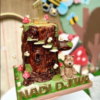 Kue ulang tahun baby Djiwa juga tampak cukup unik. Sesuai dengan tema ulang tahunnya, kue tersebut berbentuk seperti batang pohon yang dihinggapi oleh beberapa lebah kecil. Pada bagian atasnya terdapat angka 1 yang melambangkan usia baby Djiwa. Dan pada bagian depannya tertulis nama Nadi Djiwa. Foto: Instagram/@nadinelist