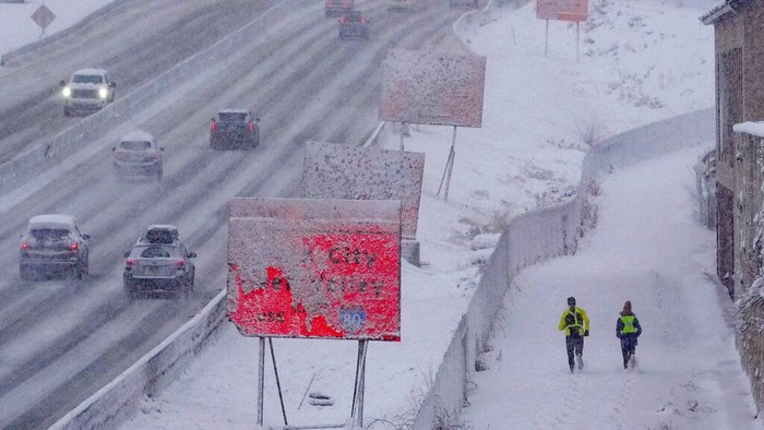 Runners negotiate snow covered paths along Interstate 80 in Salt Lake City, Utah., on Wednesday, Feb. 22, 2023. Brutal winter weather hammered the northern U.S. Wednesday with “whiteout” snow, dangerous wind gusts and bitter cold, shutting down roadways, closing schools and businesses and prompting dire warnings for people to stay home.  (Francisco Kjolseth /The Salt Lake Tribune via AP)