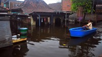 Warga menggunakan perahu melintasi jalan yang tergenang banjir di Dukuh Tanggulangin, Jati Wetan, Kudus, Jawa Tengah.