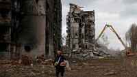 Seorang wanita bereaksi saat dia berjalan melewati lingkungannya melewati blok apartemen yang hancur akibat konflik Rusia-Ukraina di Mariupol, Ukraina yang dikuasai Rusia, 15 Februari 2023. Genap setahun invasi Rusia ke Ukraina sejak dimulai pada 24 Februari tahun lalu. REUTERS/Alexander Ermochenko