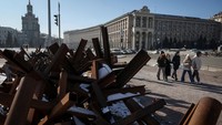 Orang-orang berjalan di jalan dekat konstruksi anti-tank saat invasi Rusia ke Ukraina berlanjut, di Kyiv tengah. REUTERS/Gleb Garanich  