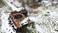 Sebuah tank Rusia yang hancur berkarat di tengah invasi Rusia ke Ukraina, dekat desa Posad-Pokrovske, barat laut kota Kherson. Dua rumah di tanah tak bertuan antara pasukan Rusia dan Ukraina rusak parah akibat penembakan, tidak ada listrik pusat atau pemanas dan ladang di sekitarnya banyak ditambang. REUTERS/Nacho Doce