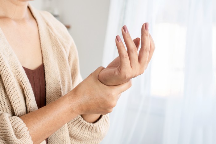 woman suffering from wrist pain, numbness, or Carpal tunnel syndrome hand holding her ache joint