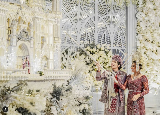 Aurel Hermansyah dan Atta Halilintar juga memilih kue ulang tahun mewah berbentuk istana. Pada bagian depannya terdapat miniatur pengantin yang mengenakan busana pengantin adat Minang, sama seperti yang dikenakan oleh Aurel dan Atta di hari bahagianya itu. Foto: Instagram/@lenovellecake