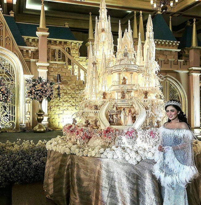 Menggelar pernikahan dengan tema negeri dongeng, Rachel Vennya tampil bak seorang putri yang berdiri di samping kue pernikahannya. Kue pernikahannya itu tampak begitu mewah berbentuk istana. Kala itu pasangan yang kini telah menjadi mantan suaminya, Okin juga tampil mengenakan kostum seperti seorang pangeran. Foto: Instagram/@lenovellecake