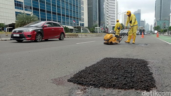 Petugas Bina Marga melakukan penambalan jalan berlubang di Jalan MH Thamrin, Jakarta, Jumat (24/2/2023).