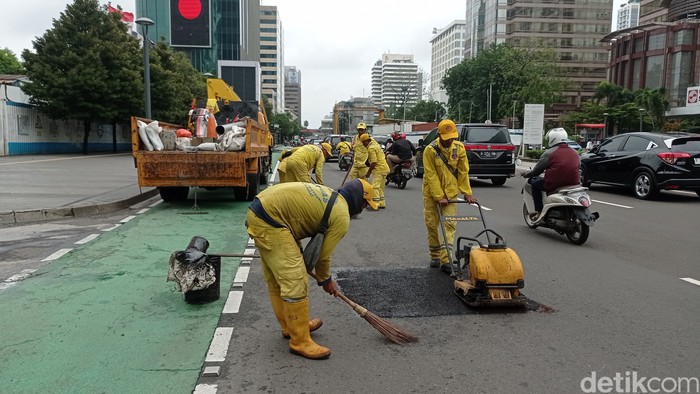 Petugas Bina Marga melakukan penambalan jalan berlubang di Jalan MH Thamrin, Jakarta, Jumat (24/2/2023).