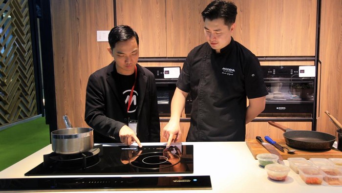 Christo, finalis Master Chef Indonesia session 6, bersama Jemmi Liem, Product Manager Lini Cooking Modena, mendemonstrasikan penggunaan kompor hybrid dengan tungku kombinasi gas dan induksi BM 8722 AABK di JCC, Senayan, Kamis (23/2/2023).