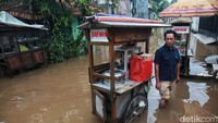 Meski banjir, warga tetap beraktivitas normal, seperti pedagang ini yang tetap berjualan.