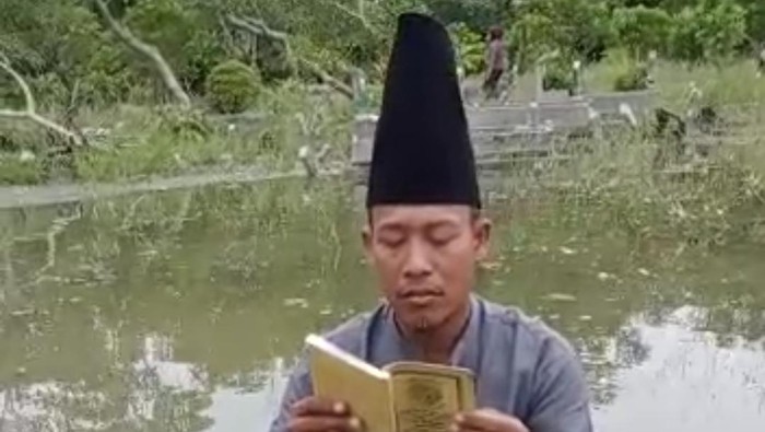 Pria gresik baca yasin di tengah banjir