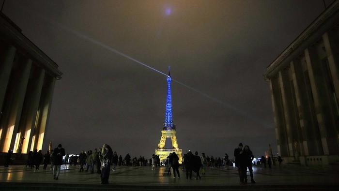 Setahun Perang Ukraina, Cahaya Buri-Kuning 'Balut' Menara Eiffel Lampu yang menghiasi Menara Eiffel di Paris, Prancis, menyala dengan warna biru dan kuning melambangkan bendera nasional Ukraina saat peringatan setahun invasi Rusia.