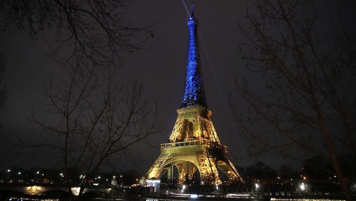 Lampu yang menghiasi Menara Eiffel di Paris, Prancis, menyala dengan warna biru dan kuning melambangkan bendera nasional Ukraina saat peringatan setahun invasi Rusia.