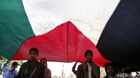 Massa aksi membentangkan bendera Palestina dalam aksi tersebut.