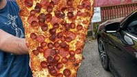 Pizza pepperoni ini disajikan dengan ukuran yang langsung bikin kenyang! Saat diangkat, panjang satu iris pizza hampir sama dengan tubuh orang dewasa. Foto: Bored Panda