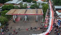 Foto udara sejumlah pelajar bergotong royong membawa bendera merah putih saat mengikuti Kirab Merah Putih di Kabupaten Batang, Jawa Tengah, Minggu (26/2/2023).