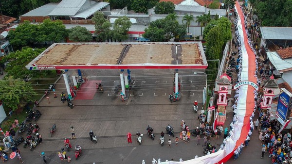 Foto udara sejumlah pelajar bergotong royong membawa bendera merah putih saat mengikuti Kirab Merah Putih di Kabupaten Batang, Jawa Tengah, Minggu (26/2/2023).