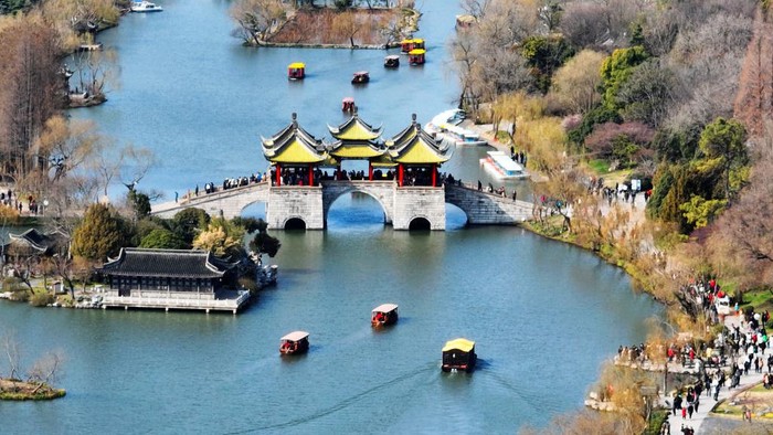 1469660663 YANGZHOU, CHINA - FEBRUARY 25: Tourists walk on a bridge at the Slender West Lake scenic spot on February 25, 2023 in Yangzhou, Jiangsu Province of China. (Photo by VCG/VCG via Getty Images)