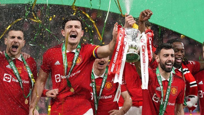 Manchester Uniteds Bruno Fernandes, centre right, and Harry Maguire, second from left, hold the trophy during celebration as they won the English League Cup final soccer match between Manchester United and Newcastle United at Wembley Stadium in London, Sunday, Feb. 26, 2023. (AP Photo/Alastair Grant)