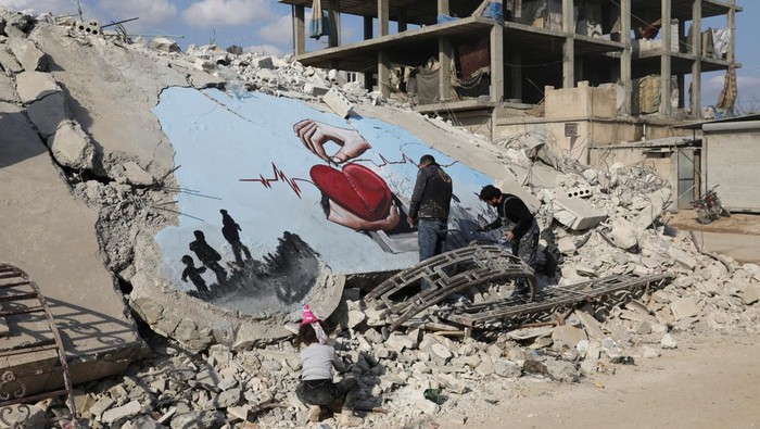 Goresan Tinta Warnai Reruntuhan Gempa Suriah Syrian artists Aziz Asmar and Salam Hamed paint street art on the rubble of damaged buildings in the aftermath of a deadly earthquake, in the rebel-held town of Jandaris, Syria February 22, 2023. REUTERS/Khalil Ashawi TPX IMAGES OF THE DAY