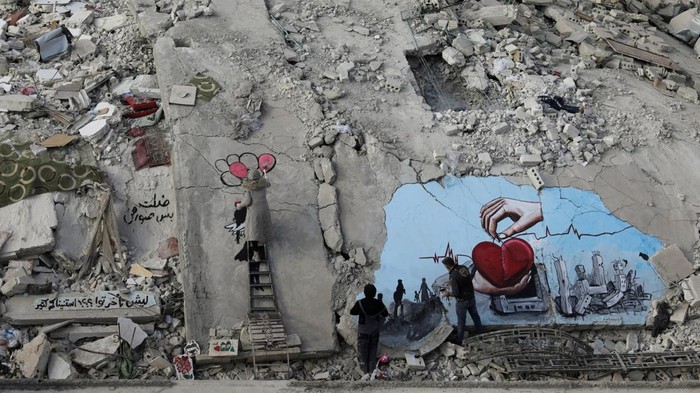 Syrian artists Aziz Asmar and Salam Hamed paint street art on the rubble of damaged buildings in the aftermath of a deadly earthquake, in the rebel-held town of Jandaris, Syria February 22, 2023. REUTERS/Khalil Ashawi     TPX IMAGES OF THE DAY