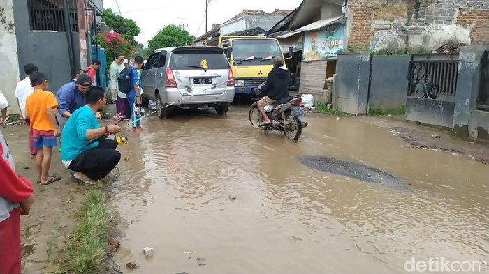 Jalan Cisarongge, Desa Mekarmukti, Kecamatan Cihampelas, Kabupaten Bandung Barat (KBB), rusak. Warga protes dengan mancing di kubangan, Senin (27/2/2023).