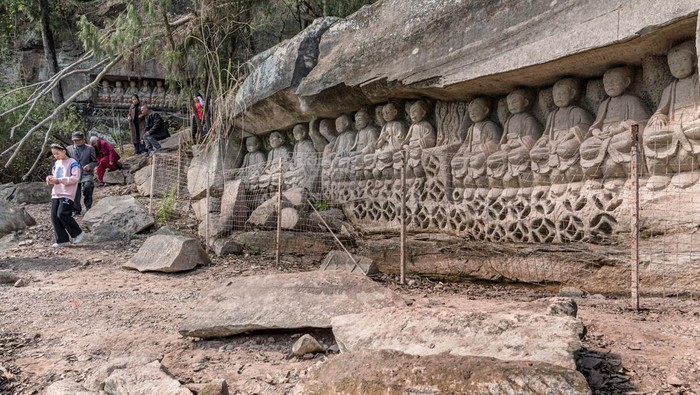 Patung Buddha Kuno Muncul dari Waduk yang Mengering di China ZIYANG, CHINA - FEBRUARY 26: A man looks at stone carved Buddhas, which appear after falling of the water level due to less rain last year at Shufangba reservoir on February 26, 2023 in Ziyang, Sichuan Province of China. (Photo by Yang Kangzhou/VCG via Getty Images)