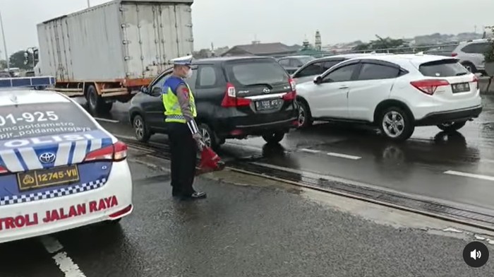 Polisi melakukan pengaturan lalu lintas di titik jalan berlubang di Km 3 Tol Dalam Kota arah Priok, Senin (27/2/2023) pagi