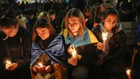Orang-orang yang membawa bendera nasional Ukraina dan tanda anti-perang berpartisipasi dalam prosesi obor di distrik tempat Kedutaan Besar Rusia berada di Roma. AP/Alessandra Tarantino