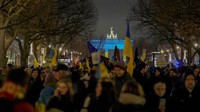 Para pengunjuk rasa tiba di Gerbang Brandenburg, diterangi dengan warna bendera Ukraina, selama demonstrasi untuk menandai peringatan pertama invasi besar-besaran Rusia ke Ukraina, di Berlin, Jerman. Setahun berlalu, perang Rusia-Ukraina belum menunjukkan tanda-tanda mereda. AP/Markus Schreiber