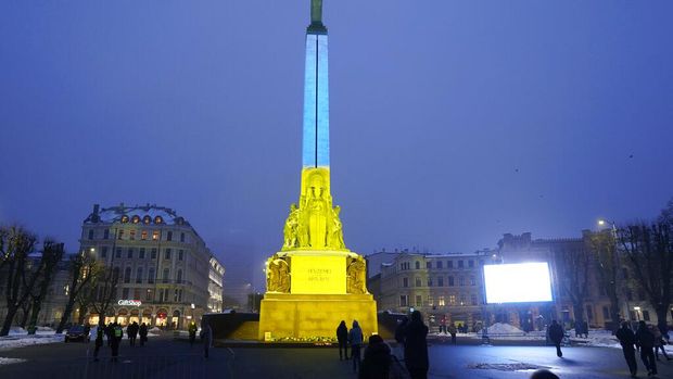 The Monument of Freedom is illuminated with the colors of the Ukrainian national flag to mark the one-year anniversary of Russia's invasion of the country, in Riga, Latvia, Friday, Feb. 24, 2023. (AP Photo/Roman Koksarov)